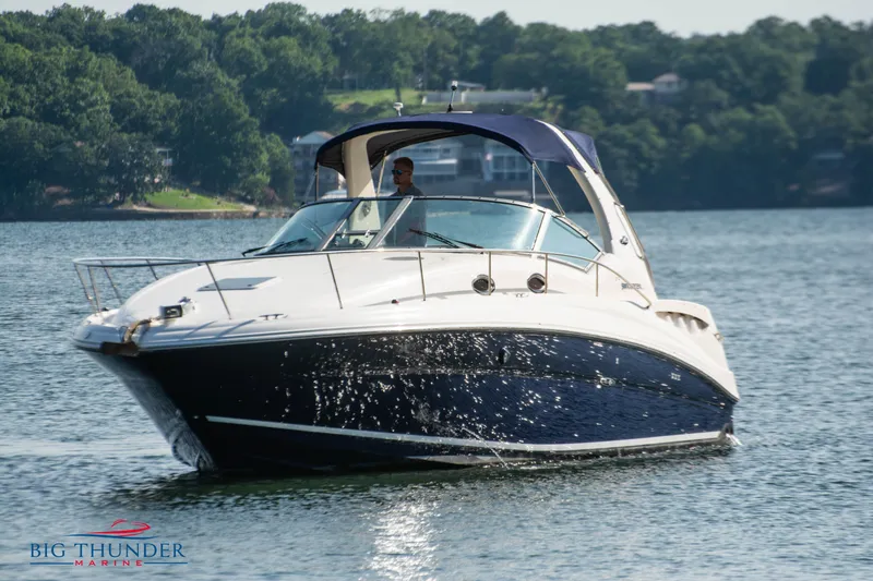 Slide: The Image of 2004 Sea Ray Sundancer 320 cruising on a serene lake with lush green shoreline. - 2