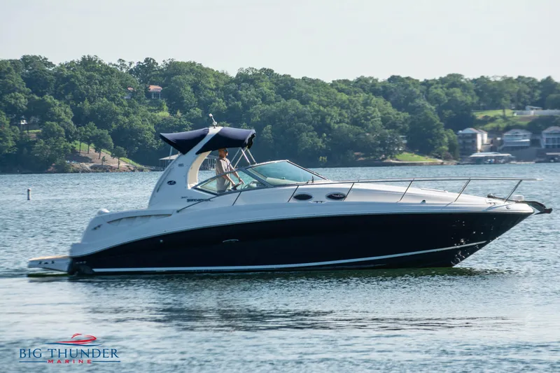 Slide: The Image of 2004 Sea Ray Sundancer 320 cruising on a serene lake with lush green shoreline. - 4