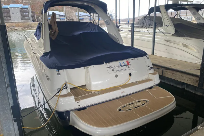 Slide: The Image of 2004 Sea Ray Sundancer 320 docked, covered, with visible swim platform and marina background. - 7