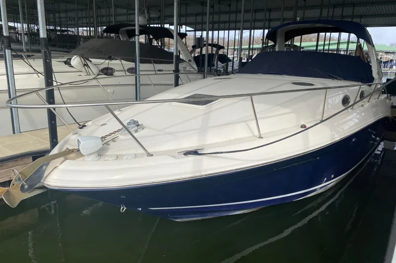 Slide: The Image of 2004 Sea Ray Sundancer 320 docked in a marina, featuring sleek design and blue hull. - 8