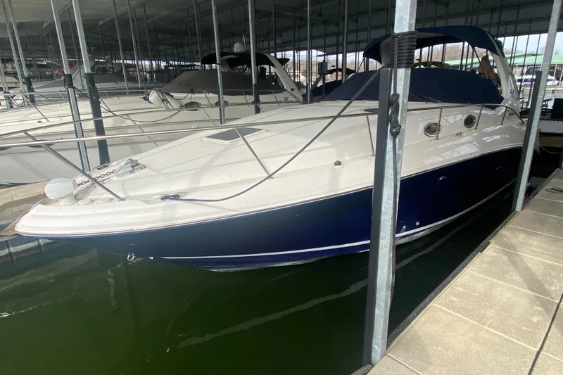 Slide: The Image of 2004 Sea Ray Sundancer 320 docked in a marina, featuring sleek design and blue hull. - 9