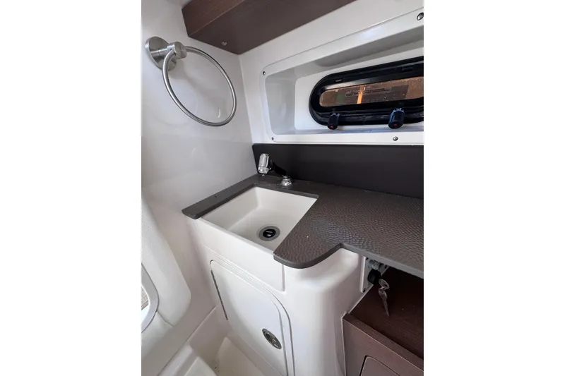 Slide: The Image of 2024 Sea Ray SDX 290 Outboard interior sink area with window and countertop. - 17