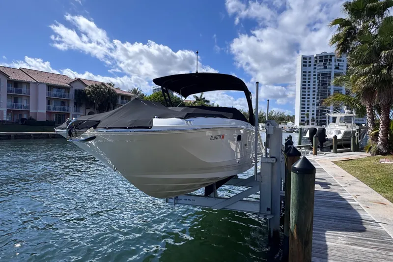 Slide: The Image of 2024 Sea Ray SDX 290 Outboard boat docked, with waterfront buildings and palm trees in the background. - 2