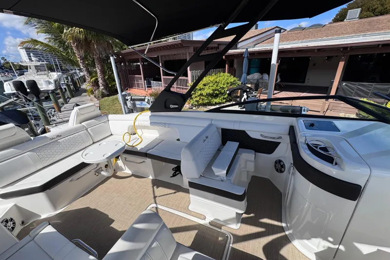 Slide: The Image of 2024 Sea Ray SDX 290 Outboard boat interior with seating and table, docked near palm trees. - 26