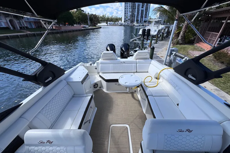 Slide: The Image of 2024 Sea Ray SDX 290 Outboard boat interior with white seating, docked by a scenic waterfront. - 31