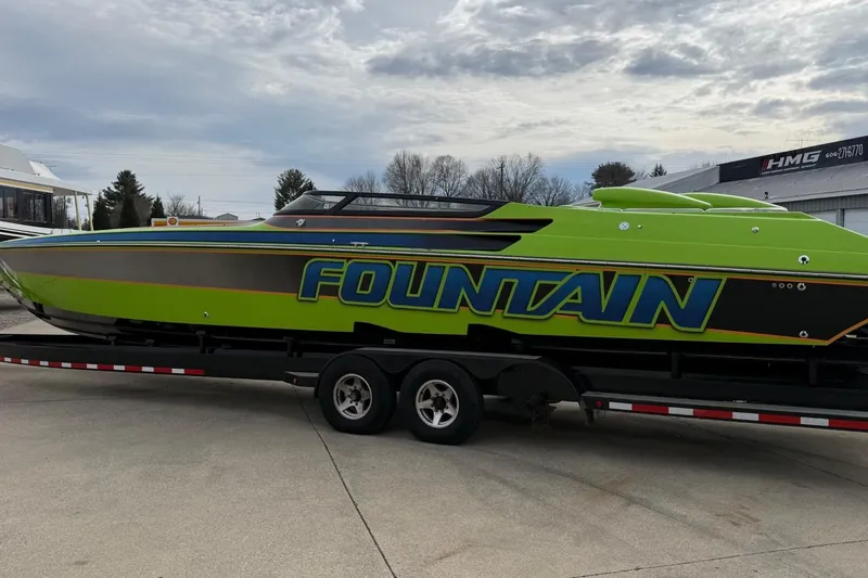 Slide: The Image of 2002 Fountain 42 Lightning speedboat in vibrant green on a trailer, under cloudy skies. - 4