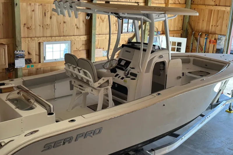 Slide: The Image of 2019 Sea Pro 239 Deep V CC boat in wooden garage, showcasing interior and helm. - 2