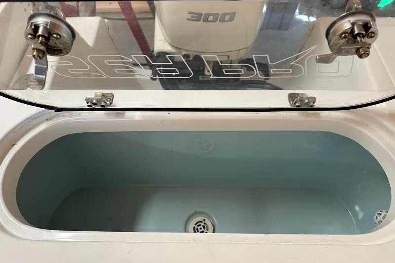 Slide: The Image of Livewell on 2019 Sea Pro 239 Deep V CC boat, featuring a clear lid and secure latches. - 7