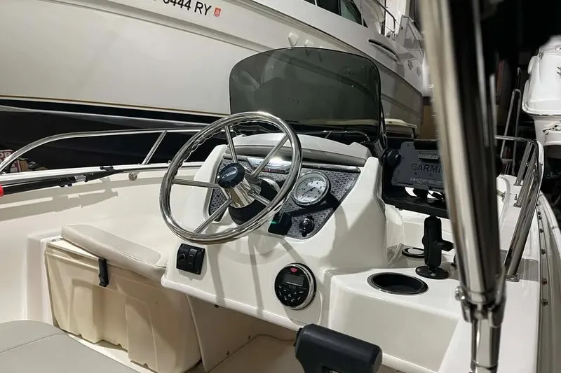 Slide: The Image of 2023 Boston Whaler 160 Super Sport boat interior with steering wheel and dashboard controls. - 7