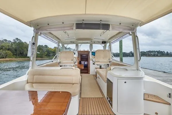 Slide: The Image of 2018 MJM 40z yacht interior with beige seating and wooden accents, docked by a scenic shoreline. - 24