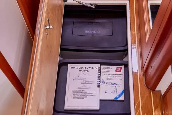 Slide: The Image of Open storage compartment with manuals in a 2018 MJM 40z boat. - 38