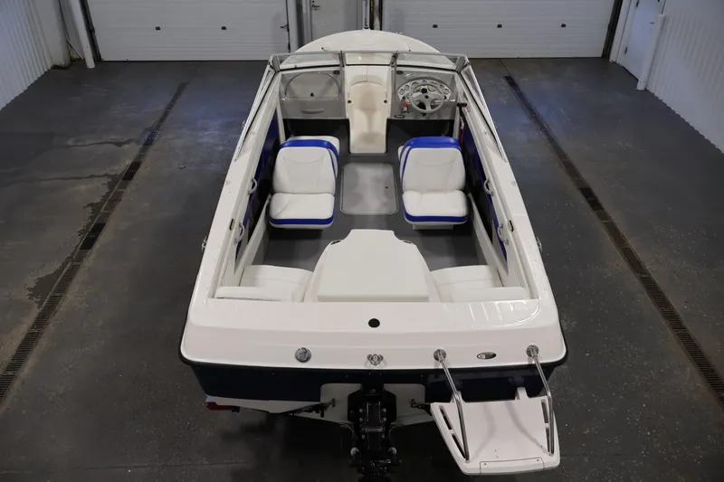 Slide: The Image of 2006 Bayliner 195 Bowrider boat with white and blue interior, viewed from above in a garage. - 10