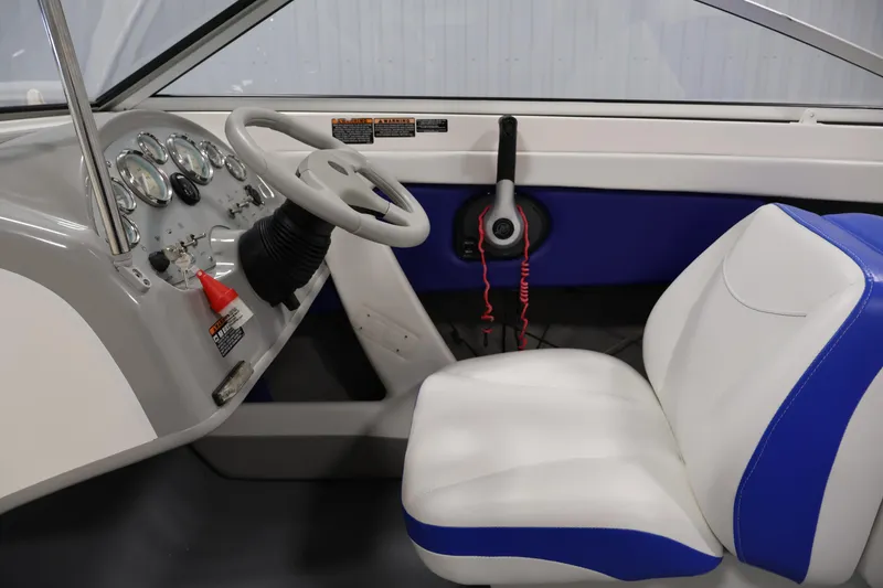 Slide: The Image of 2006 Bayliner 195 Bowrider interior with steering wheel, gauges, and white-blue seating. - 13