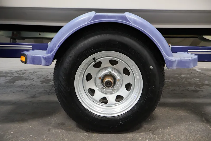 Slide: The Image of Trailer wheel of a 2006 Bayliner 195 Bowrider boat, featuring a purple fender. - 48