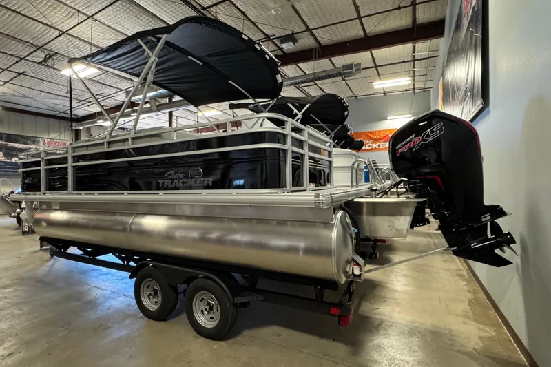 Slide: The Image of 2026 Sun Tracker SportFish 20 DLX pontoon boat with Mercury engine in showroom. - 3