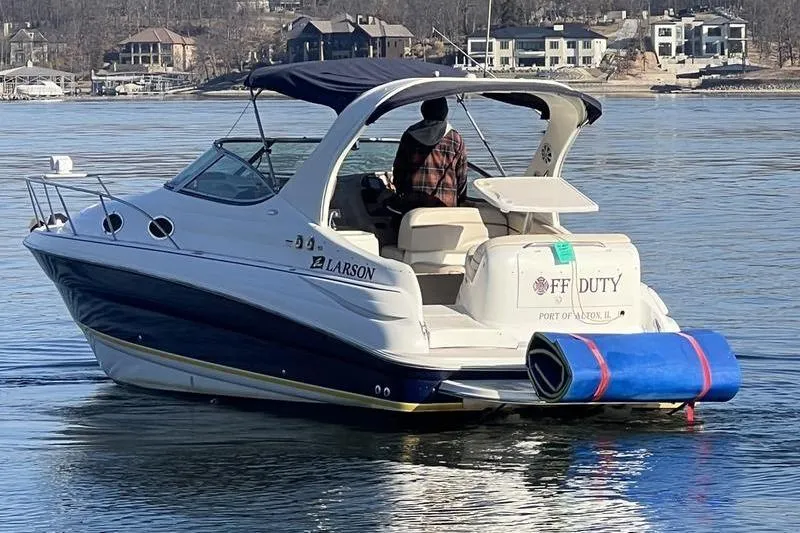 Slide: The Image of 2005 Larson Cabrio 290 boat on calm water, featuring a covered cockpit and rear deck. - 4