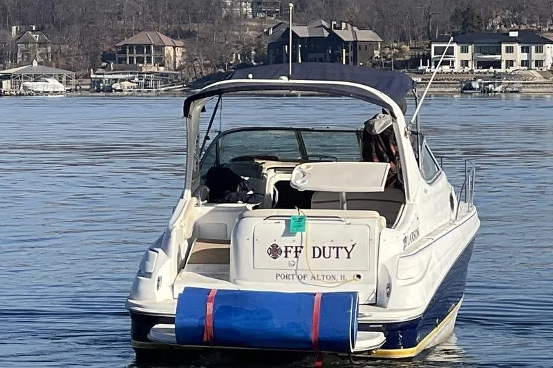 Slide: The Image of 2005 Larson Cabrio 290 boat docked on a calm lake with waterfront homes. - 5