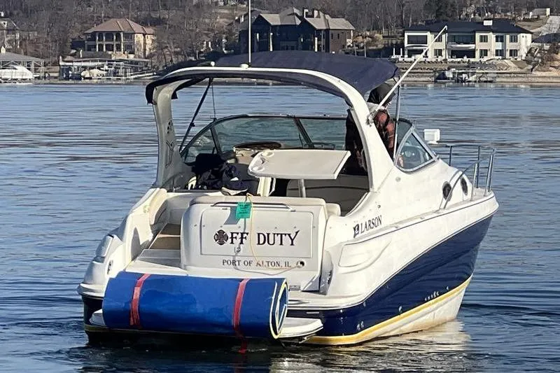 Slide: The Image of 2005 Larson Cabrio 290 boat on water, rear view, with "Off Duty" signage. - 6