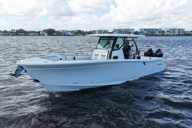 Slide: The Image of 2026 Blackfin 332 CC boat cruising on a calm lake with modern buildings in the background. - 13