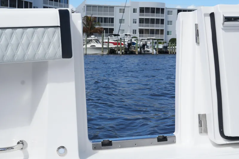Slide: The Image of 2026 Blackfin 332 CC boat door open, overlooking marina with water and buildings. - 19