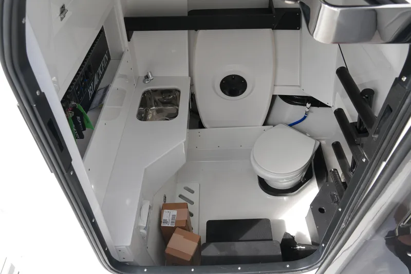 Slide: The Image of Interior of 2026 Blackfin 332 CC boat featuring compact bathroom with sink and toilet. - 65