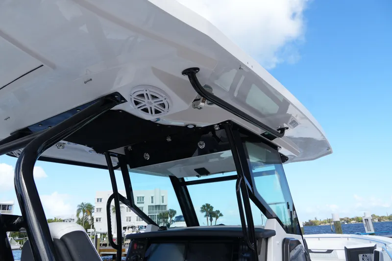 Slide: The Image of 2026 Blackfin 332 CC boat console with T-top and speaker, docked by waterfront homes. - 66