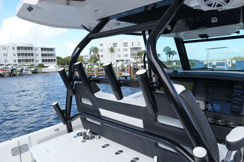 Slide: The Image of 2026 Blackfin 332 CC boat interior with rod holders and control panel, dockside view. - 68