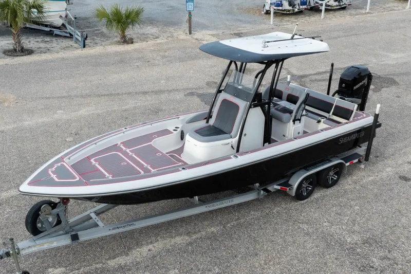 Slide: The Image of 2018 ShearWater 26 Carolina boat on trailer, black hull, red accents, parked outdoors. - 37