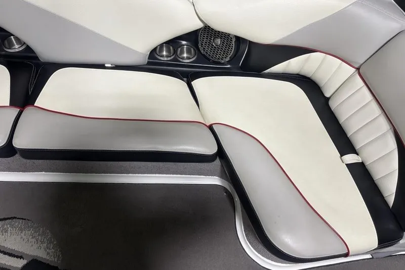Slide: The Image of 2015 Malibu Wakesetter 247 LSV interior seating with white and gray upholstery, red trim, and cup holders. - 16