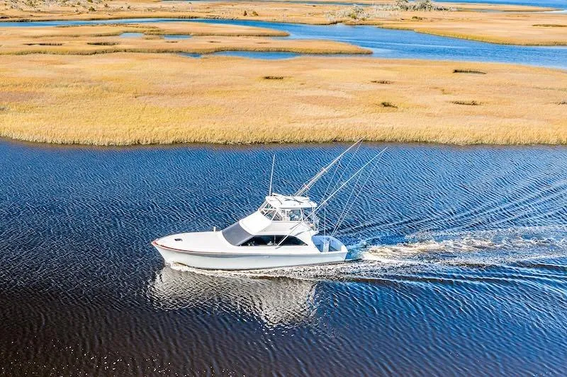 Slide: The Image of 1991 Ocean Yachts 53 Super Sport cruising through scenic marshland waters. - 10