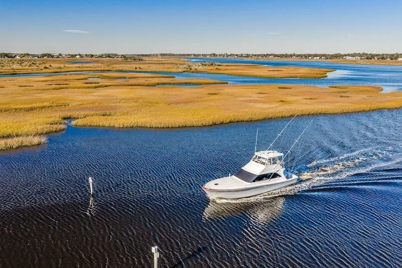 Slide: The Image of 1991 Ocean Yachts 53 Super Sport cruising through scenic marshland waters. - 9