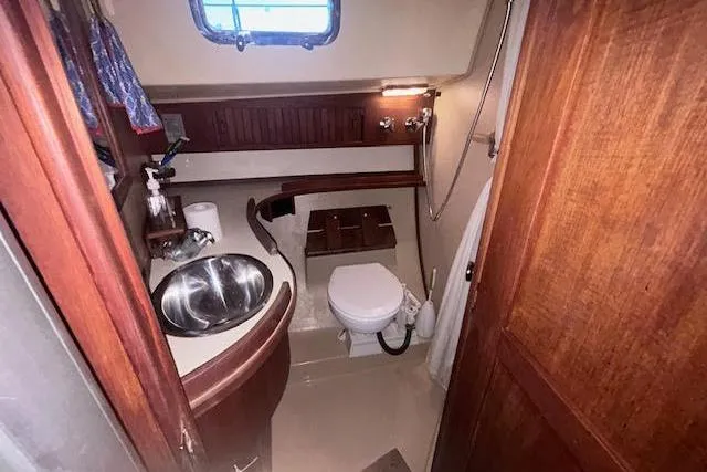 Slide: The Image of 1994 Island Packet 320 yacht bathroom with sink, toilet, and wooden cabinetry. - 10