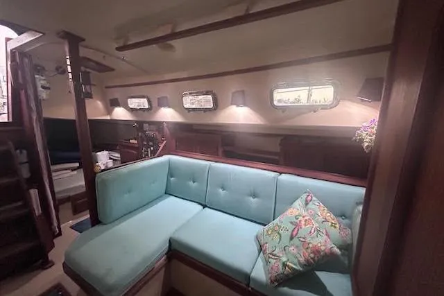 Slide: The Image of Interior of 1994 Island Packet 320 sailboat with teal seating and decorative pillow. - 15