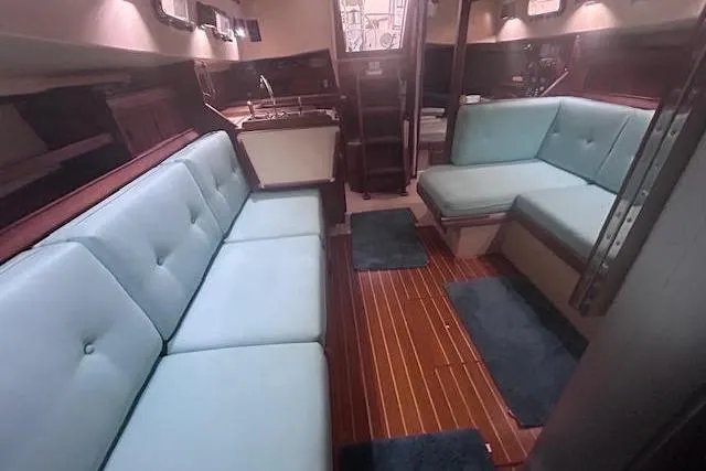 Slide: The Image of Interior of 1994 Island Packet 320 sailboat with blue seating and wooden flooring. - 16