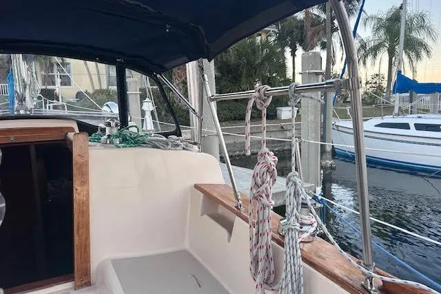 Slide: The Image of 1994 Island Packet 320 sailboat cockpit with ropes, docked near palm trees. - 3