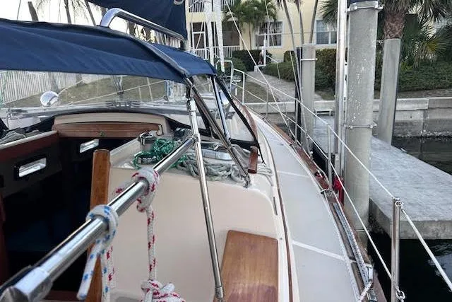 Slide: The Image of 1994 Island Packet 320 sailboat docked, featuring a blue canopy and wooden deck details. - 4