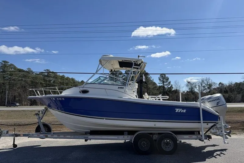 Slide: The Image of 2005 Triton 2486 CC boat on trailer, blue and white, parked outdoors. - 0