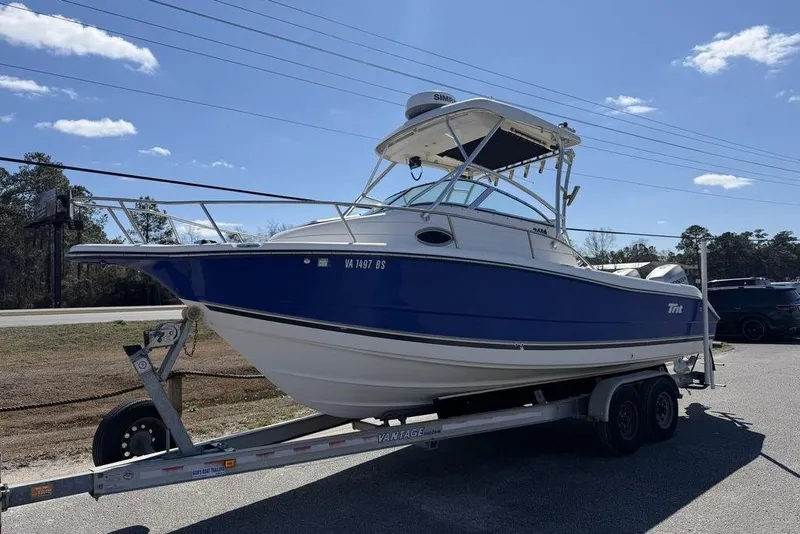 Slide: The Image of 2005 Triton 2486 CC boat on trailer under clear blue sky. - 1