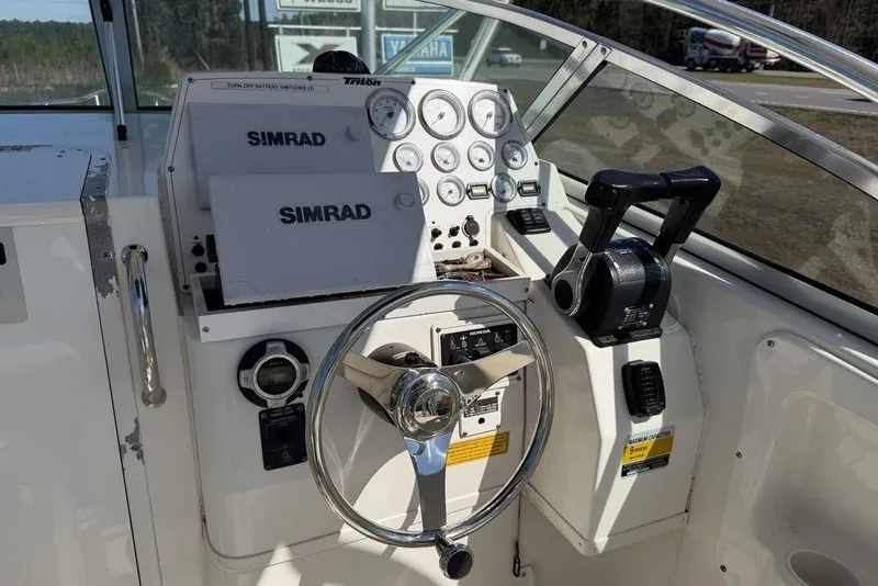 Slide: The Image of 2005 Triton 2486 CC boat dashboard with Simrad navigation system and steering wheel. - 11