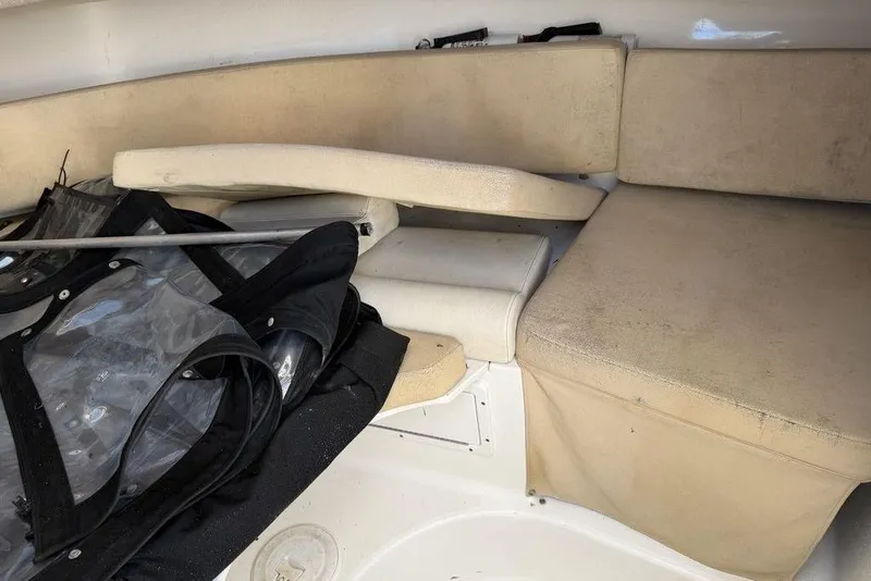 Slide: The Image of 2005 Triton 2486 CC boat interior with beige seating and stored equipment. - 14