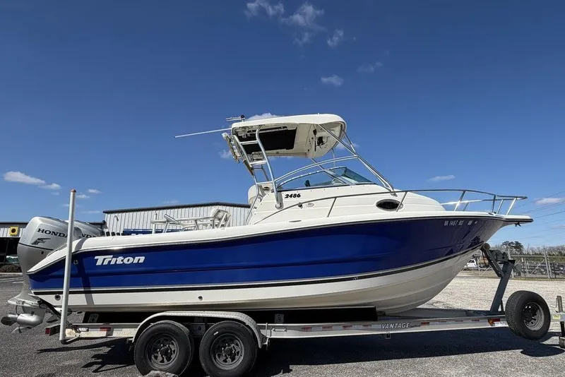 Slide: The Image of 2005 Triton 2486 CC boat on trailer under clear blue sky. - 6