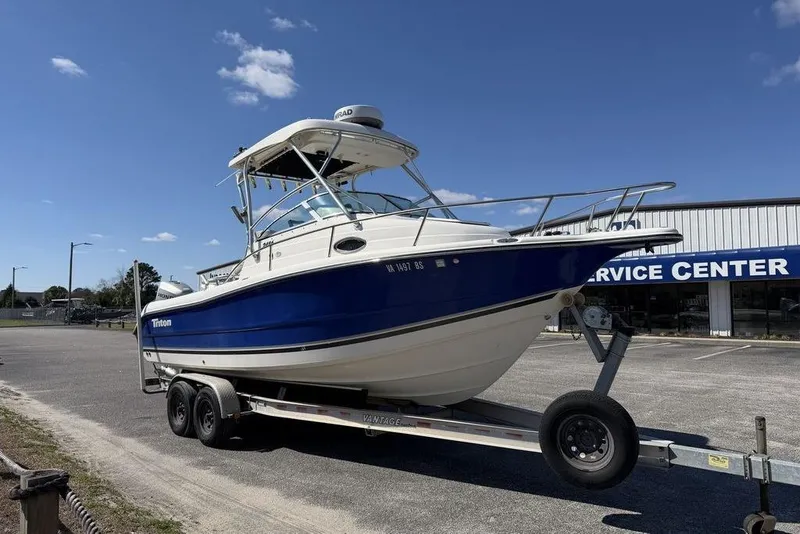 Slide: The Image of 2005 Triton 2486 CC boat on trailer at service center under clear blue sky. - 7