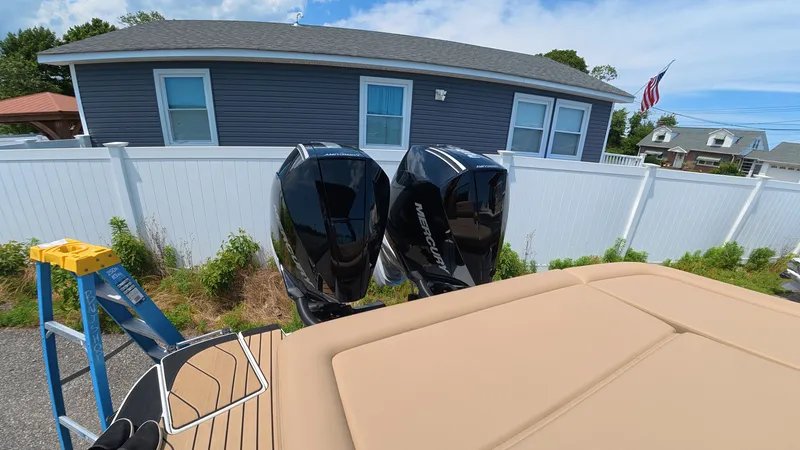 Slide: The Image of Two outboard motors on a boat, with a house and fence in the background. - 2