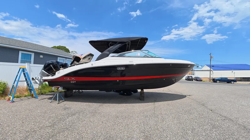 Slide: The Image of A 2026 Sea Ray SLX 280 Outboard is parked on a lot. It features a black and white design with a red stripe. - 30