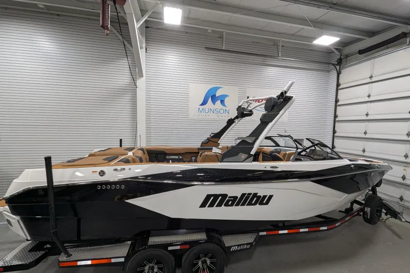Slide: The Image of 2026 Malibu Wakesetter 26 LSV boat in showroom, black and white design, on trailer. - 1