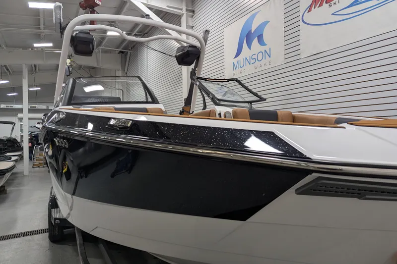 Slide: The Image of 2026 Malibu Wakesetter 26 LSV boat in showroom, featuring sleek black and white design. - 6