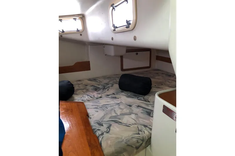 Slide: The Image of 1998 Catalina 320 yacht interior cabin with patterned bedding and portholes. - 28
