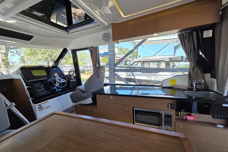 Slide: The Image of Interior of 2019 Jeanneau NC 1095 boat with helm, kitchen, and seating area. - 5