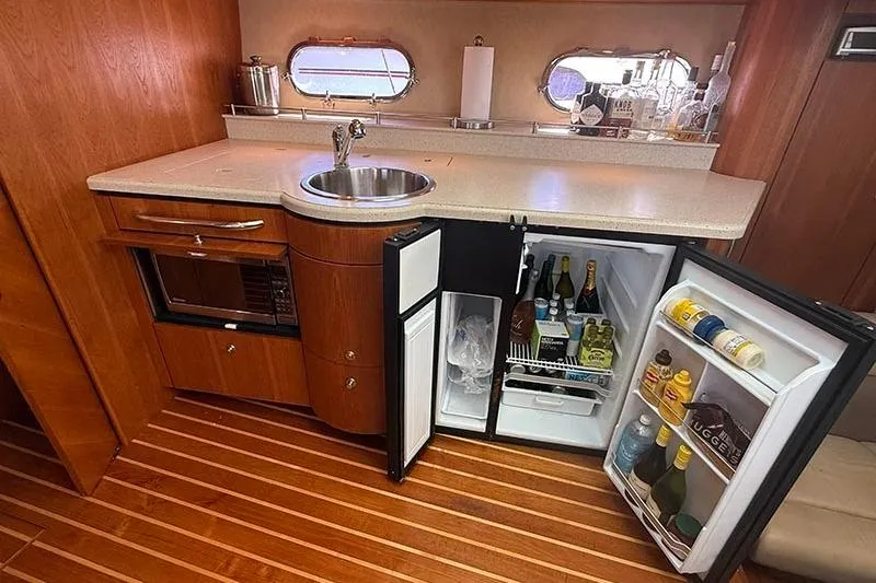 Slide: The Image of 2008 Tiara Yachts 3900 Sovran galley with open fridge, sink, and wooden flooring. - 12