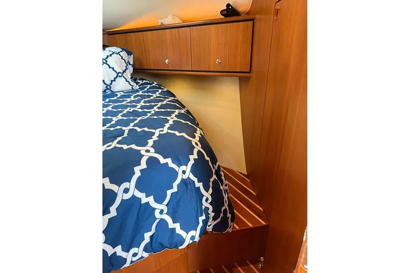 Slide: The Image of 2008 Tiara Yachts 3900 Sovran cabin with blue patterned bedding and wooden cabinetry. - 22
